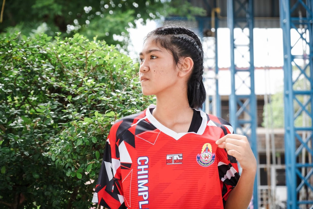 Young woman in a red sports jersey looks away.