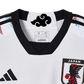 White Japan soccer jersey featuring anime-inspired design with Itachi Uchiha from Naruto, black crows, Konoha symbol, Adidas logo, and Japan national team crest