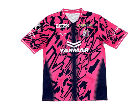 Cerezo Osaka 2026/27 home jersey fan version front, bright pink shirt with navy geometric shards, YANMAR sponsor, club crest on chest, CAPCOM patch, J.League sleeve patch